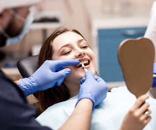 a young woman choosing the color of her teeth with a dentist