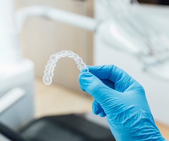 Dentist holding clear aligner with blue glove