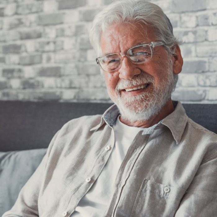 an older man smiling while at home