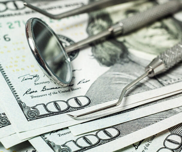 dental tools laying on a pile of dollar bills