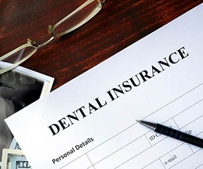A dental insurance form against a brown desk