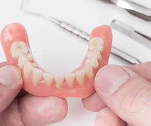 a closeup of dentures in someone’s hand