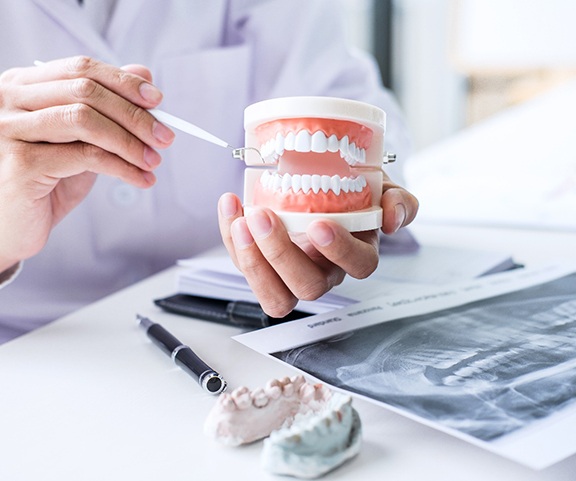 Denture dentist in Sparta holding a model of teeth