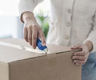 Woman using box cutter to open a package