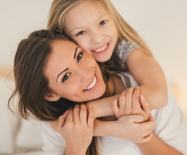 Smiling mother and daughter holding each other