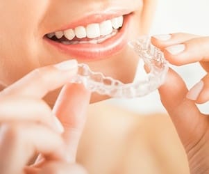 Woman placing Invisalign tray in her mouth