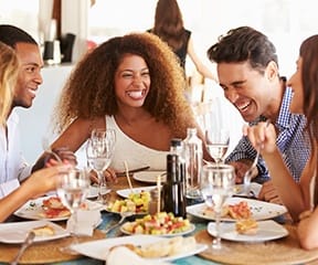 Eating a meal with friends, enjoying benefits of dental implants