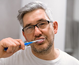 Older man practicing dental implant care in Sparta