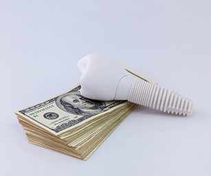 Model of a dental implant on a stack of money