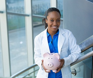 Implant dentist in Sparta holding a piggy bank