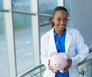 smiling dentist holding a pink piggy bank