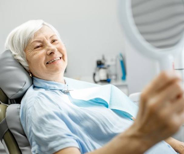elderly woman admiring her smile in the mirror
