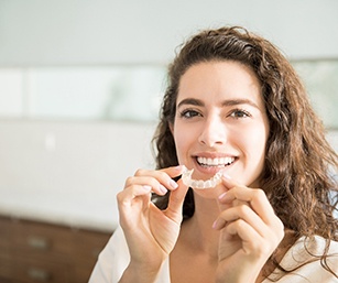 Woman smiling while holding clear aligner