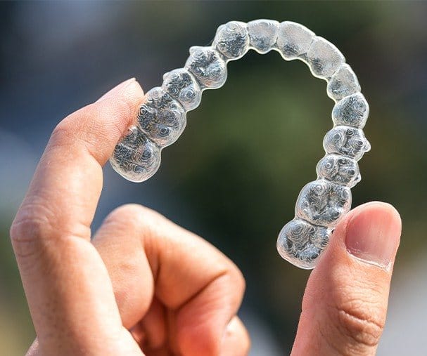 Hand holding clear Invisalign tray