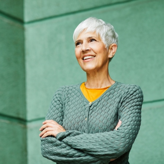 older woman smiling with her arms crossed