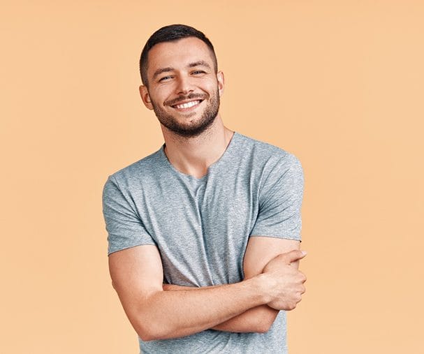 Smiling, handsome with attractive teeth standing against neutral background