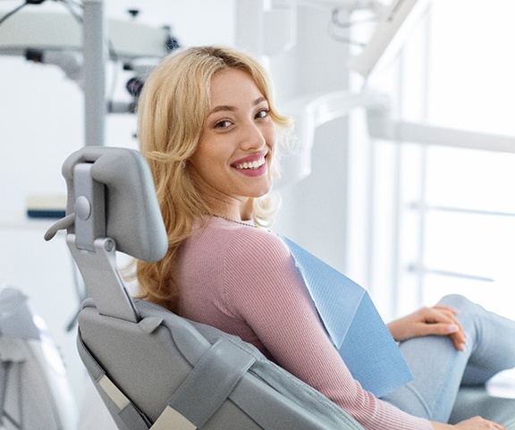Blonde woman sitting in dental chair and smiling