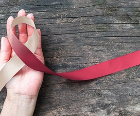 Hand holding ribbon for oral cancer awareness