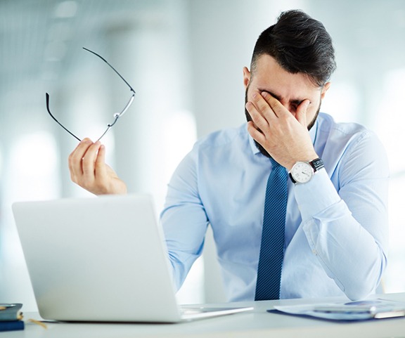 Exhausted man sitting at desk, struggling with sleep apnea symptoms