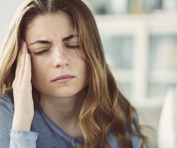 Woman touching the side of her head, suffering from a headache