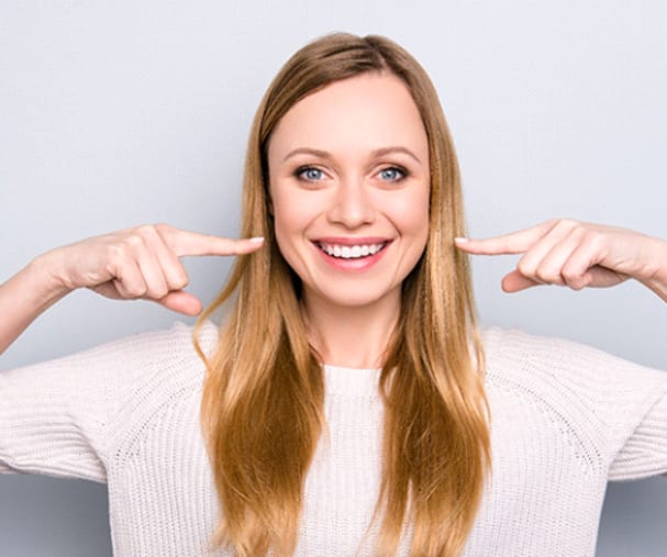 Woman pointing to smile after teeth whitening in Sparta