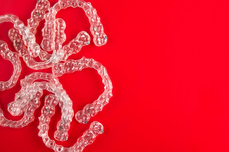 a pile of clear aligners laying on a red surface