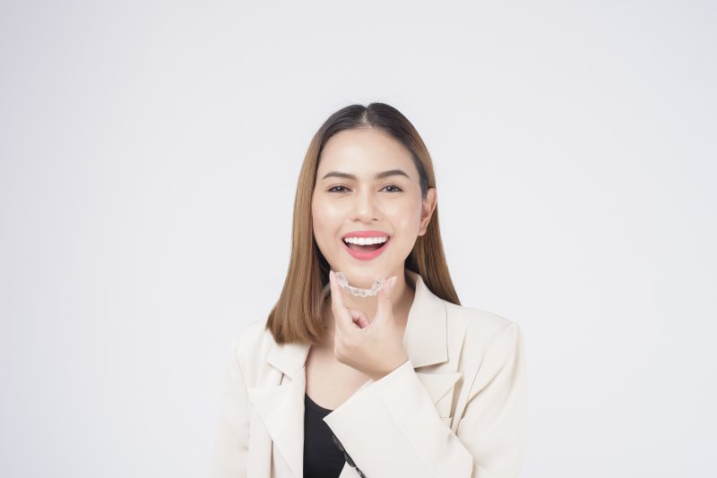 person holding Invisalign aligner and smiling