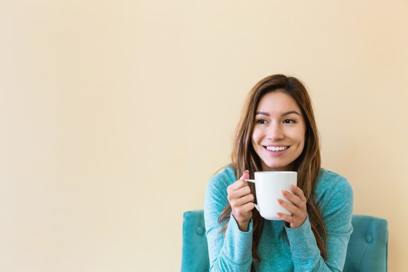woman smiling while drinking coffee