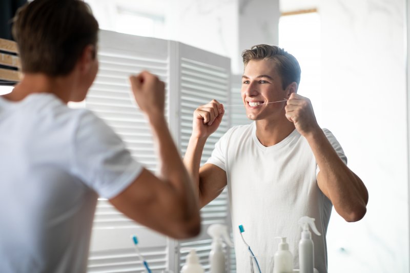 young man flossing teeth