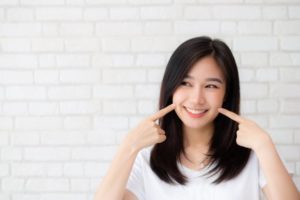 Patient pointing towards her smile after receiving cosmetic dentistry.