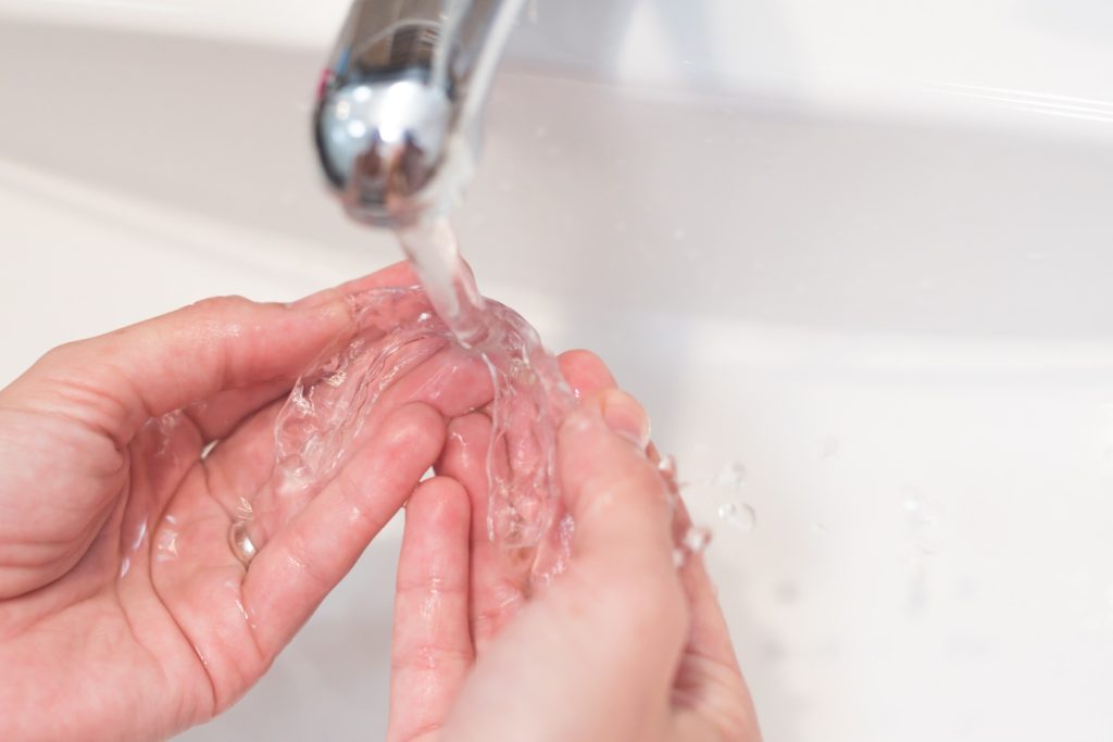 Patient holding Invisalign aligners under running water