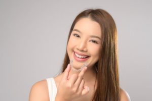 Smiling young woman holding Invisalign aligner