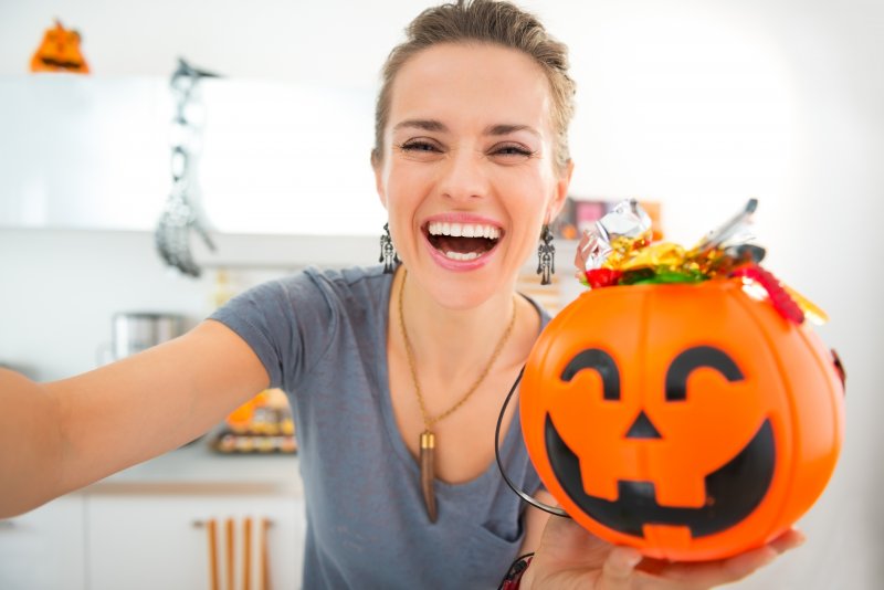 A woman preparing for trick-or-treaters wearing her new Invisalign aligners