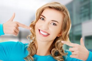Woman smiling and gesturing towards her mouth.